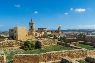 Fototapeta na wymiar Victoria (Rabat), Goza, Malta - September 25th 2019: The medieval ruins inside the Cittadella (Citadel) with the Cathedral of the Assumptionand and Chapel of Saint Joseph.
