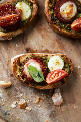 Crostini with tomato, salami and olive pesto on wooden background. Top view. Copy space,