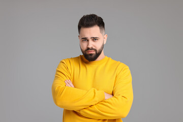 Portrait of sad man with crossed arms on light grey background