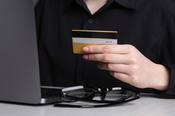 Online payment. Woman with laptop and credit card at white wooden table, closeup