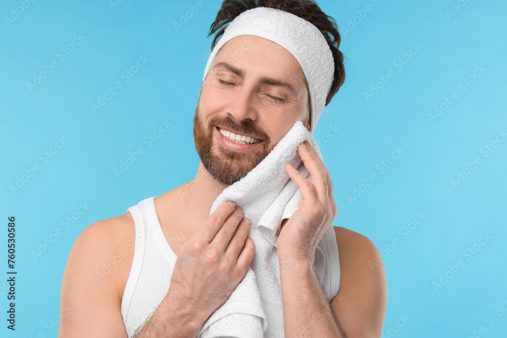 Poster Washing face. Man with headband and towel on light blue background