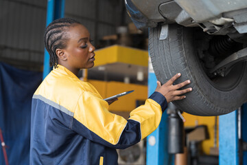 Female mechanic working at garage. Professional female mechanics checks, repair and maintenance tires car at auto car repair service. Car service and Maintenance concept - obrazy, fototapety, plakaty