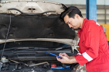 Male mechanic working at garage. Professional Asian male mechanics checks, repair and maintenance under hood of at auto car repair service. Car service and Maintenance concept