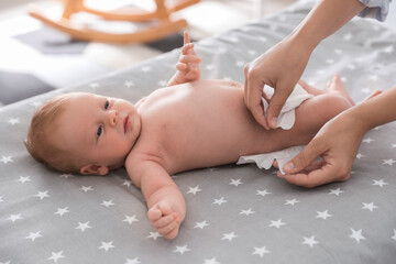 Mother changing her baby's diaper on bed