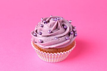 Delicious cupcake with bright cream and sprinkles on pink background