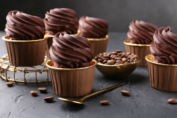 Delicious chocolate cupcakes and coffee beans on black textured table