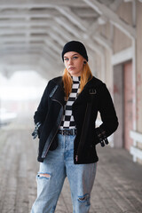 Fototapeta premium Edgy female model with piercings, beanie and blond hair. Dark tones and blurry background