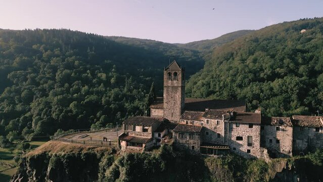 Castellfollit de la Roca at sunrise - 4K Drone Aerial Flyover - epic landscape of churches, cliffs, canyons, villages and forests - Catalonia Spain - incredible