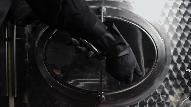 Turning the valve and opening the sealed valve hatch of the vinifier tank valve of red and white wines in the factory. Close-up 