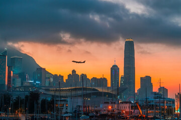 Urban landscape with silhouettes of skyscraper buildings and a city with a plane taking off in the...