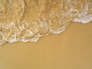 Sea foam on yellow sandy beach top view background