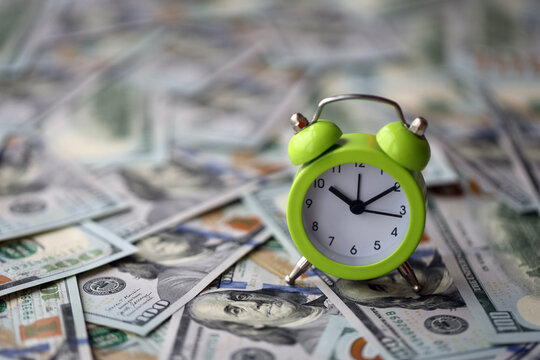 Alarm clock on hundred dollar bills banknotes. Background of time management, business and deadline concept