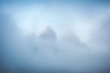 Foto op Plexiglas The sharp peaks of Tre Cime di Lavaredo are visible through the mist. Sexten Dolomiti, South Tyrol, Europe. © Leonid Tit