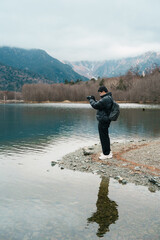 man  tourist travel Kamikochi National Park, happy Traveler sightseeing Taisho pond with mountain, Nagano Prefecture, Japan. Landmark for tourists attraction. Japan Travel, Destination and Vacation