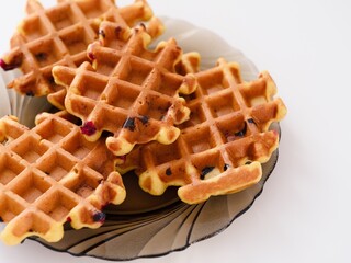 Four tasty homemade waffles on a plate on a white table.