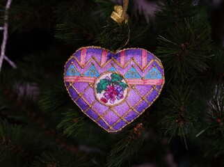 A cross stitched Christmas Timeless Elegance ornament on to a Christmas tree. This heart shape purple Christmas ornament with grapes embroidered and made by myself.