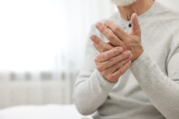 Arthritis symptoms. Man suffering from pain in hand at home, closeup. Space for text