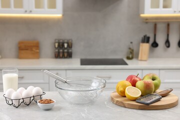 Fototapeta na wymiar Metal whisk, bowl, grater and different products on gray marble table in kitchen