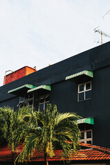 Black concrete façade of the building with windows against the background of palm trees and the sky. Stylish Concrete Wall