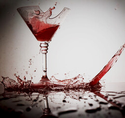 Red wine splashes flowing into a broken glass