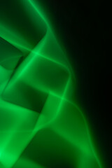 Green abstract smooth lines on a black background twisting into a vertical chain. Vertical orientation. Copy space