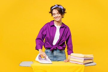 Young smiling happy calm fun woman she wear purple shirt casual clothes do housework tidy up...