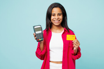 Little happy kid teen girl wear pink shirt white t-shirt hold wireless modern bank payment terminal to process acquire credit card isolated on plain blue cyan background. Childhood lifestyle concept.