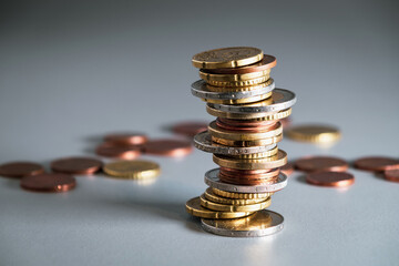 Leaning, inclined pole with euro coins. Stack of coins with blurred coins in the background