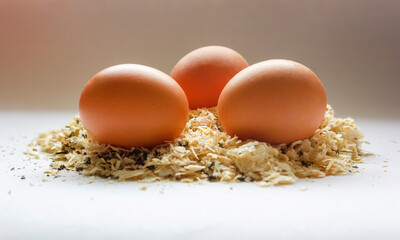 Three eggs lie in sawdust or hay laid by a chicken.