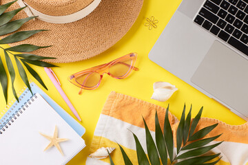 Beach-inspired remote work station.Top view photo of straw hat, pink sunglasses, notepads, palm...