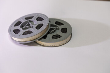 Two old school 8mm film reels against a white background with a shadow falling to the right. 