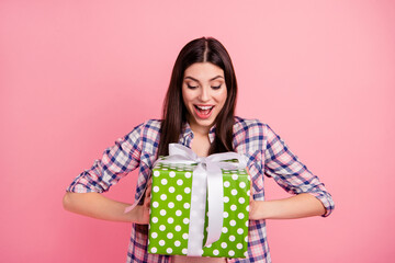 Portrait of nice-looking attractive cute charming lovely cheerful cheery straight-haired lady wearing checked shirt holding in hands big large green box isolated over pink background