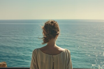 A woman standing on a balcony overlooking the ocean. Perfect for travel and vacation concepts - Powered by Adobe