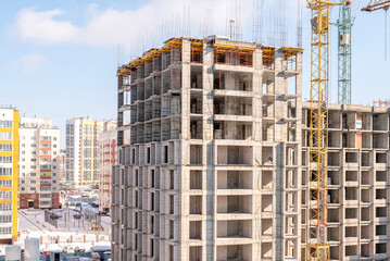 A house under construction against the background of already built residential blocks. Construction and new houses.