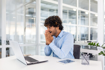 Happy joyful hispanic businessman inside office reading online happy news on laptop, young...