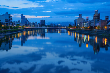 A serene portrait of the Kamo River at dusk, with the city lights reflecting on the water's surface, Japanese minimalistic style,