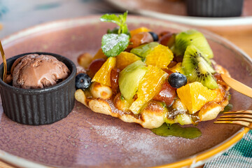Delicious fruit dessert with pastry in powdered sugar and  with chocolate ice cream on a plate close-up - 760624533
