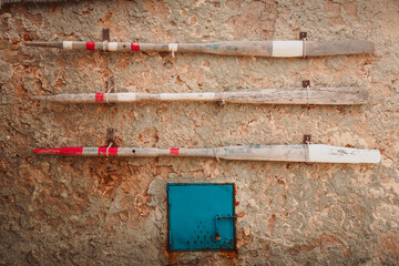 Three ancient wooden oars hanging on a wall of ancient Sicilian fishing village