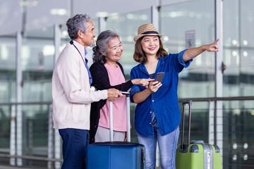 Group of Asian family tourist passenger with senior is using mobile application to call pick up taxi at airport terminal for transportation during their vacation travel and long weekend holiday