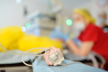 Checking up oxygenation with fingertip pulse oximeter during surgery in operating room in clinic. Saturation blood of oxygen. Monitoring of the patient condition