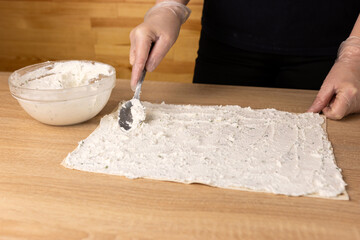A layer of cheese filling is placed on the unfolded pita bread. Preparation of pita bread roll.