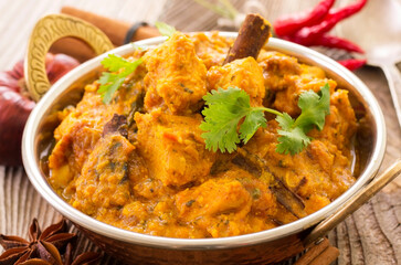 Traditional Indian chicken curry served with spices and chicken pieces as close-up in a kadai bowl