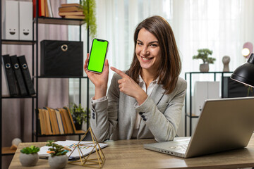 Caucasian young businesswoman holding smartphone with green screen chroma key mock up recommend...