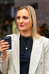 woman in a white jacket holding a coffee cup