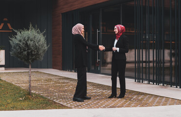 Two successful business Muslim woman shaking hands finishing up meeting.