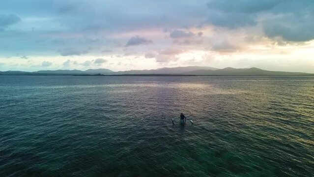 As the day wanes, a fisherman in a small boat drifts across the waters off Palawan's coast, under a sky painted with the colors of dusk.