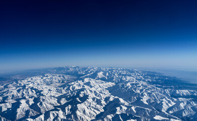 Top of snowy mountain range on blue sky background