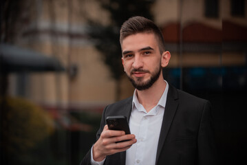 A young happy business man using a phone mobile outdoor near the office buliding.