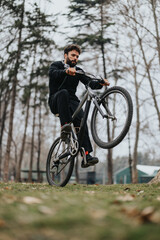 Fototapeta na wymiar Focused man performing bicycle stunt in a forested park setting.