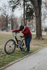 A young boy leans on his bicycle in a park, a moment capturing the essence of childhood and outdoor activity.